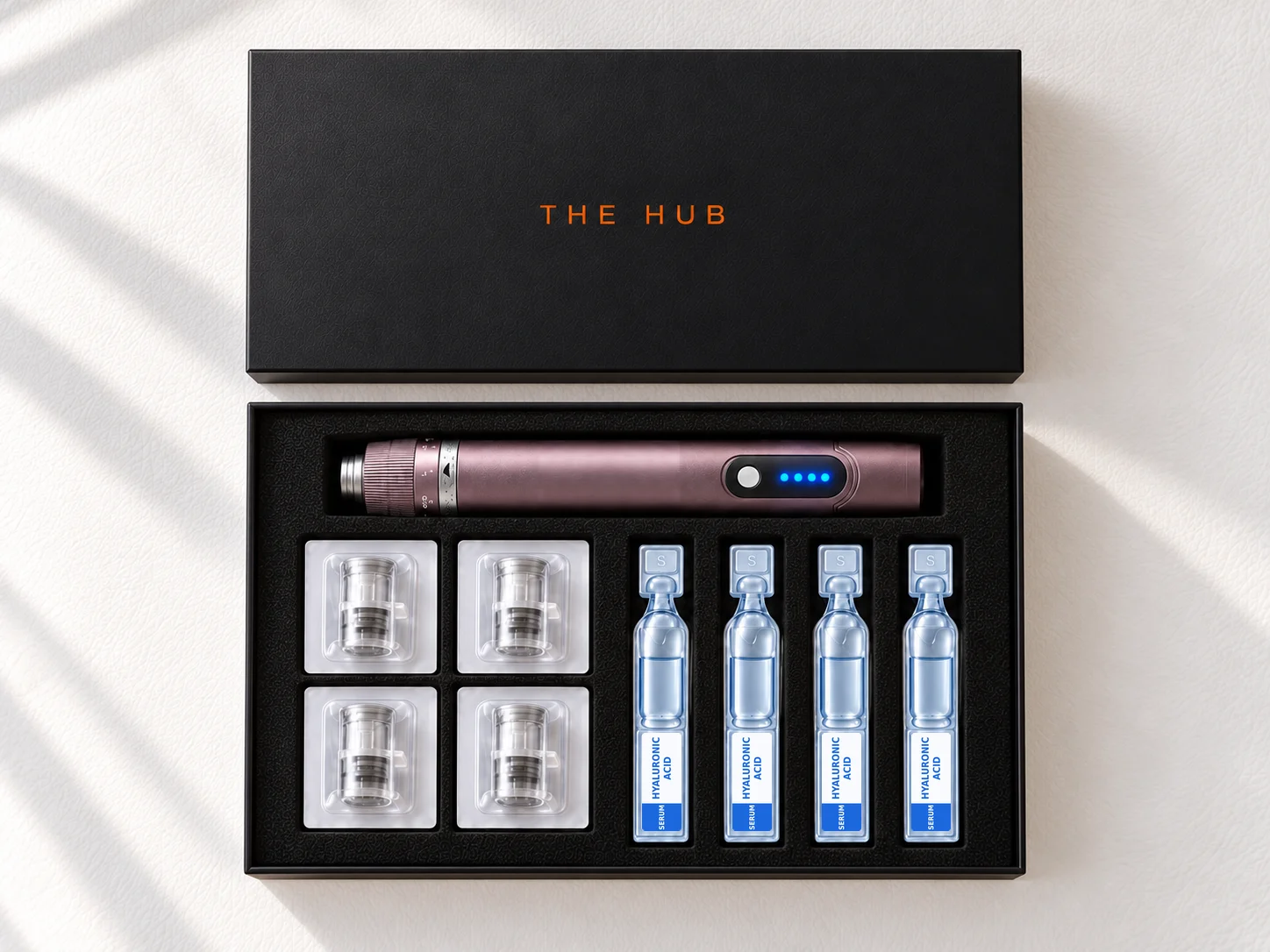 The Hub microneedling kit: professional microneedling pen, four needle cartridges and four hyaluronic acid serums in a black box